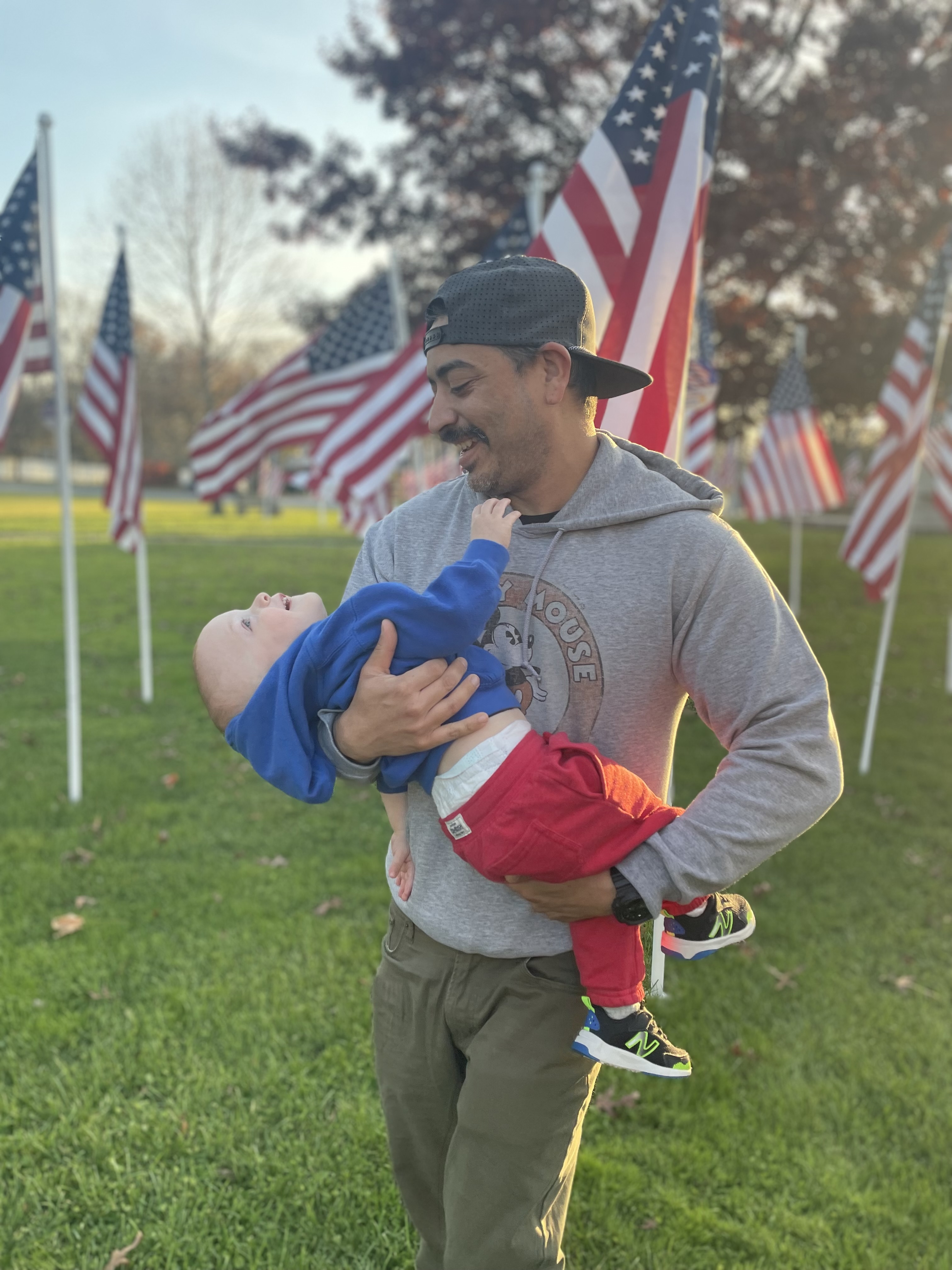 A picture of me holding my son in front of American flags 